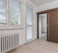 I Predaj 3- izbového bytu v Dúbravke - Interiér 3-izbového bytu s radiátorom, žalúziami a podlahou s dreveným dekorom.