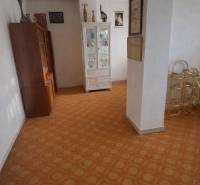 Bývajte vo svojom : dom a  pozemok 690 m², Veľké Ripňany 77.000,-EUR - Interiér rodinného domu s vitrínou a kobercovou podlahou, dekoráciami a obrazmi na stenách.