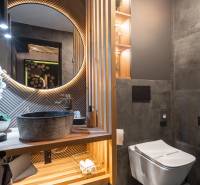| Luxusný dvojúrovňový mezonet v Starom Meste - Kúpeľňa v 3-izbovom byte s okrúhlym zrkadlom, rustikálnym umývadlom a dekoratívnym osvetlením.
