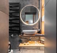 | Luxusný dvojúrovňový mezonet v Starom Meste - Kúpeľňa v 3-izbovom byte s okrúhlym zrkadlom a umývadlom na drevenej doske.