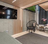 | Luxusný dvojúrovňový mezonet v Starom Meste - Obývačka v 3-izbovom byte so zavesenou stoličkou, TV a dekoratívnym obkladom.