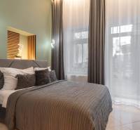 | Luxusný dvojúrovňový mezonet v Starom Meste - Spálňa v 3-izbovom byte s veľkým oknom, závesmi a pohodlnou posteľou.