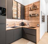 | Luxusný dvojúrovňový mezonet v Starom Meste - Kuchyňa v 3-izbovom byte s podlahou s dreveným dekorom a tmavými skrinkami.