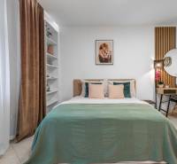 I Luxusný byt v historickom centre Bratislavy - Spálňa s posteľou, zelenou prikrývkou, pracovným stolom a dekoratívnymi prvkami v 2-izbovom byte.