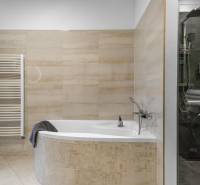 I Luxusný byt v historickom centre Bratislavy - Kúpeľňa v 2-izbovom byte s rohovou vaňou, obkladanými stenami a sprchovým kútom.