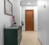 I Luxusný byt v historickom centre Bratislavy - Chodba v 2-izbovom byte s kvetom, zrkadlom a drevenými dverami.