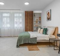 I Luxusný byt v historickom centre Bratislavy - Spálňa 2-izbového bytu s veľkou posteľou, pestrými doplnkami a nábytkom v svetlých tónoch.