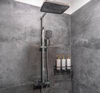 I Luxusný byt v historickom centre Bratislavy - Sprchový kút s tmavými obkladmi a nástennými dávkovačmi v 2-izbovom byte.