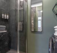 I Luxusný byt v historickom centre Bratislavy - Kúpeľňa v 2-izbovom byte s preskleným sprchovým kútom, uterákmi a dekoráciami.