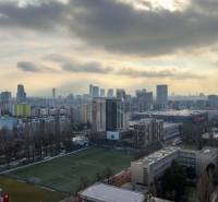 I na predaj 2i byt v komplexe Tri Veže na Bajkalskej - Panoráma Bratislavy z Bajkalskej, ukazuje mestskú krajinu s budovami a športovým ihriskom.