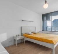 I na predaj 2i byt v komplexe Tri Veže na Bajkalskej - Svetlá spálňa v 2-izbovom byte s posteľou a podlahou s dreveným dekorom.