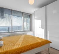 I na predaj 2i byt v komplexe Tri Veže na Bajkalskej - Spálňa s veľkými oknami, žltým prehozom a vstavanou skriňou v 2-izbovom byte.