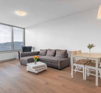 I na predaj 2i byt v komplexe Tri Veže na Bajkalskej - Obývacia izba 2-izbového bytu s podlahou s dreveným dekorom, pohovkou a jedálenským stolom.