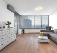 I na predaj 2i byt v komplexe Tri Veže na Bajkalskej - Obývačka v 2-izbovom byte s pohovkou a podlahou s dreveným dekorom, svetlý priestor.