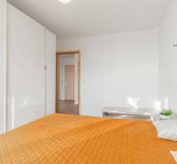 I na predaj 2i byt v komplexe Tri Veže na Bajkalskej - Spálňa v 2-izbovom byte s oranžovou prikrývkou a veľkou bielou skriňou.