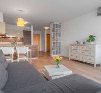 I na predaj 2i byt v komplexe Tri Veže na Bajkalskej - Obývačka s podlahou s dreveným dekorom a kuchynským kútom v 2-izbovom byte.