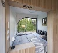 I Predaj Ecocapsule – autonómne ekologické bývanie - Spálňa so vstavanou posteľou, okrúhlym oknom a podlahou s dreveným dekorom.