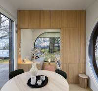 I Predaj Ecocapsule – autonómne ekologické bývanie - Sklenené dvere, drevené dekorácie, okrúhle okno a stôl s nádobami v jedálenskej časti.