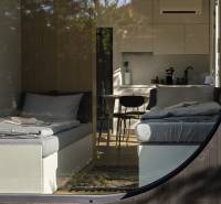 I Predaj Ecocapsule – autonómne ekologické bývanie - Interiér s dvoma posteľami, kuchyňou a podlahou s dreveným dekorom. Zvláštne nehnuteľnosti.