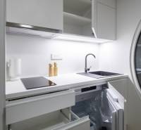 I Predaj Ecocapsule – autonómne ekologické bývanie - Kompaktná kuchynská linka v bielej farbe so spotrebičmi a úložným priestorom.