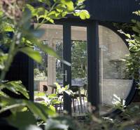 I Predaj Ecocapsule – autonómne ekologické bývanie - Sklenené dvere a kruhové okno medzi zeleňou pri zvláštnych nehnuteľnostiach v Bratislave.