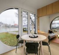 I Predaj Ecocapsule – autonómne ekologické bývanie - Kruhové okná v interiéri s výhľadom na rieku a architektúru Zvláštnych nehnuteľností.