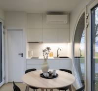 I Predaj Ecocapsule – autonómne ekologické bývanie - Interiér s bielou kuchynkou, okrúhlym stolom a veľkými oknami, podlaha s dreveným dekorom.