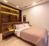 I Na predaj Luxusná vila „Tomma“ v Ubud, Bali - Spálňa vo vile s veľkou posteľou, vstavanými drevenými policami a žltým podsvietením.