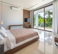 I Na predaj Luxusná vila „Tomma“ v Ubud, Bali - Svetlá spálňa vo vile s posteľou, televízorom a výhľadom na tropickú zeleň.