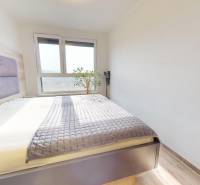 Na predaj nadštandardne zariadený 3 izb.byt, Trenčín, ul. Odevná - Spálňa v 3-izbovom byte s veľkým oknom, posteľou a podlahou s dreveným dekorom.