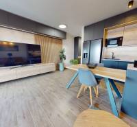 Na predaj nadštandardne zariadený 3 izb.byt, Trenčín, ul. Odevná - Obývacia izba v 3-izbovom byte s podlahou s dreveným dekorom a kuchyňou.