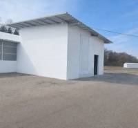 Predaj, výrobný a veľkoobchodný areál v okrese Veľký Krtíš - Výrobné priestory vo Veľkom Krtíši s bielou fasádou a veľkou bránou.