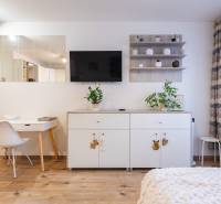 Prenájom 1-izbového bytu, Béžová, Béžová, Petržalka - REZERVOVANÉ - Interiér 1-izbového bytu s bielym nábytkom a podlahou s dreveným dekorom.