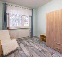 Predaj 4-izbového bytu, Vyšehradská, Vyšehradská, Petržalka - Izba v 4-izbovom byte so skriňou, kreslom a podlahou s dreveným dekorom.
