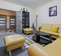 Predaj 4-izbového bytu, Vyšehradská, Vyšehradská, Petržalka - Obývačka 4-izbového bytu s koženou žltou sedačkou, sklenou vitrínou a obrazom na stene.