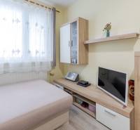 Predaj 4-izbového bytu, Vyšehradská, Vyšehradská, Petržalka - Interiér 4-izbového bytu s pohovkou, televízorom a nábytkom s dreveným dekorom.