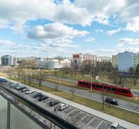 Komfortný 1,5-izbový byt s balkónom v Ružinove na predaj - Výhľad z balkóna v Bratislave - Ružinove na ulici Súmračná s električkou a parkom.