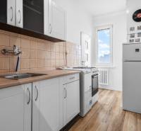 Komfortný 1,5-izbový byt s balkónom v Ružinove na predaj - Kuchyňa v 1-izbovom byte s podlahou s dreveným dekorom a bielymi skrinkami.