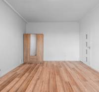 Komfortný 1,5-izbový byt s balkónom v Ružinove na predaj - Izba s bielymi stenami, podlaha s dreveným dekorom, šatník so zrkadlom, 1-izbový byt.