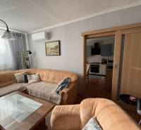 Vkusný 3 izb. byt po kompl. rekonštrukcii - Jilemnického ulica -72m2 - Obývacia izba s pohovkou, skleneným stolom a kuchyňou v 3-izbovom byte.