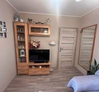 Na predaj  3-izbový byt v meste Rajec  - Izba s televízorom, zrkadlom, drevenou zostavou a pohovkou, v 3-izbovom byte.