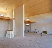 Únik z mesta, kde sa moderná architektúra stretáva s divokou prírodou? - Interiér chaty s vysokým stropom, surovo upravené steny a jemné drevené dekorácie.