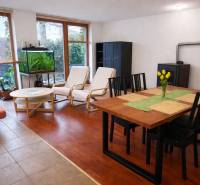 Prenájom 3-izbového bytu so záhradkou, 81m2, Pezinok-Centrum. - Obývacia izba v 3-izbovom byte s podlahou s dreveným dekorom, jedálenským stolom a akváriom.