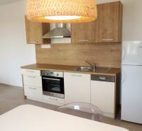 Moderná garsónka v obľúbenej Rezidencii Tematínska - Piešťany - Kuchyňa v garsónke na ulici Bodona s drevenými skrinkami, sporákom a chladničkou.