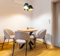 PRENÁJOM | 3i tehlový BYT, 90 m², centrum PO, balkón , ZARIADENÝ - Jemná jedáleň v 3-izbovom byte s okrúhlym stolom a kreslami, podlaha s dreveným dekorom.