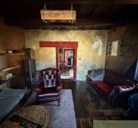 Štýlová chalupa v horskej dedinke Ratkovské Bystré - Rustikálna obývacia izba v rodinnom dome s koženými kreslami a podlahou s dreveným dekorom.