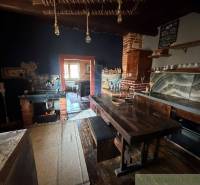 Štýlová chalupa v horskej dedinke Ratkovské Bystré - Kuchyňa v rodinnom dome so starožitným interiérom, dreveným stolom a tehlovou pecou.