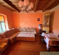 Exkluzívne: Pekná chalupa v obci Lipovec - Obývacia izba s rohovou sedačkou, podlahou s dreveným dekorom a kachľovou pecou v rodinnom dome.