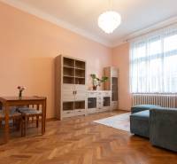 3-izbový byt s vysokými stropmi, Staré Mesto - Obývacia izba v 3-izbovom byte s podlahou s dreveným dekorom, sedačkou a nábytkom.