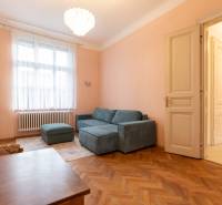 3-izbový byt s vysokými stropmi, Staré Mesto - Svetlá obývačka s pohovkou, lustrom a podlahou s dreveným dekorom v 3-izbovom byte.